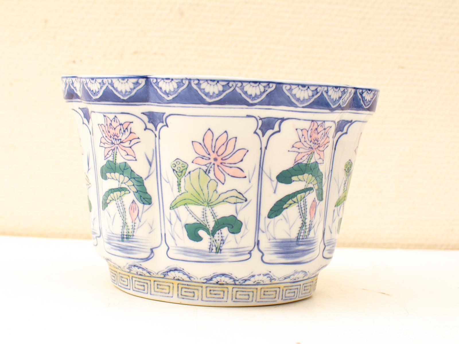 Elegant vintage porcelain bowl with hand-painted lotus flowers and green leaves on a white background.