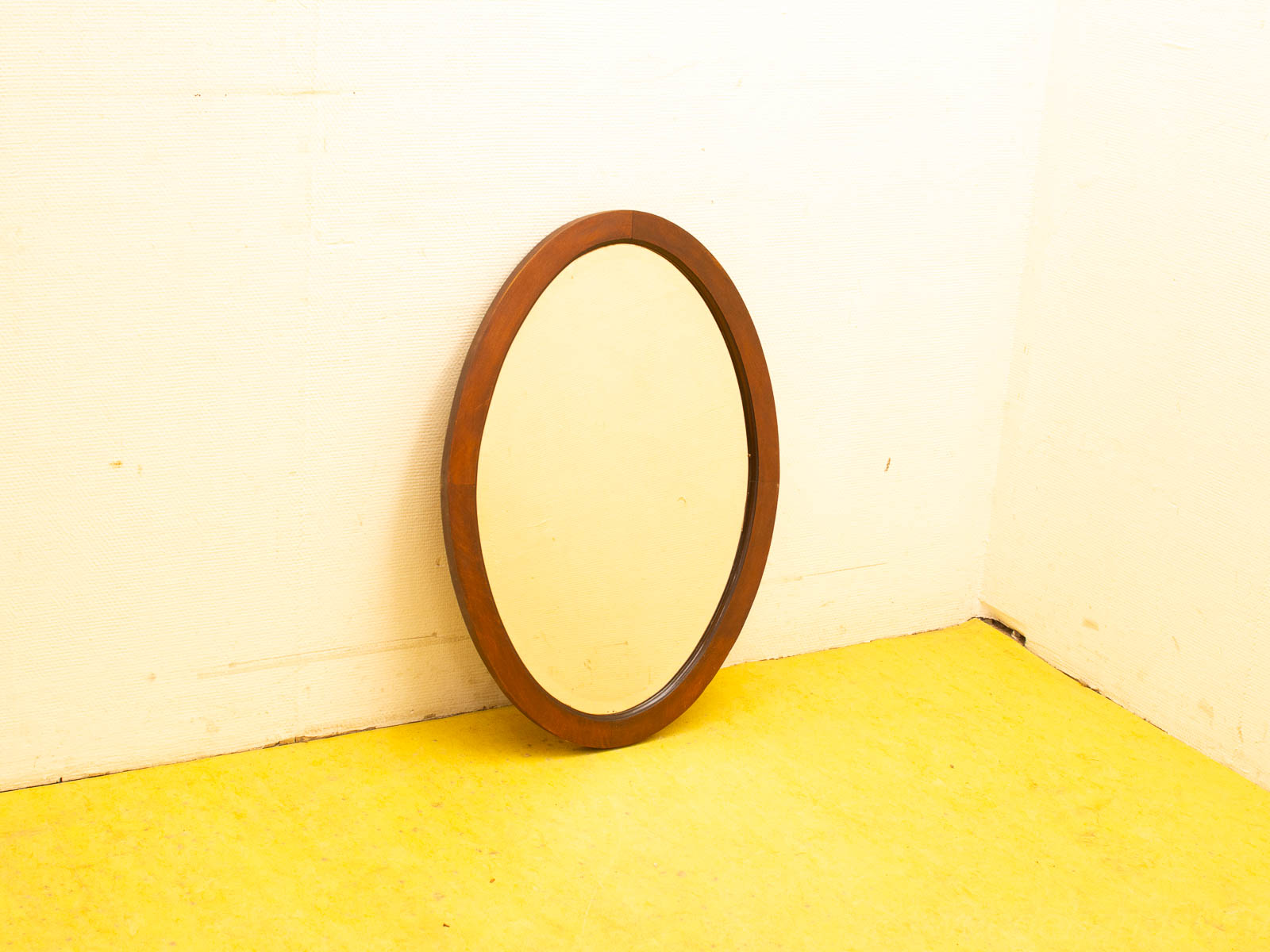 Round wooden mirror in cozy corner with vibrant yellow floor, enhancing rustic charm and simplicity.