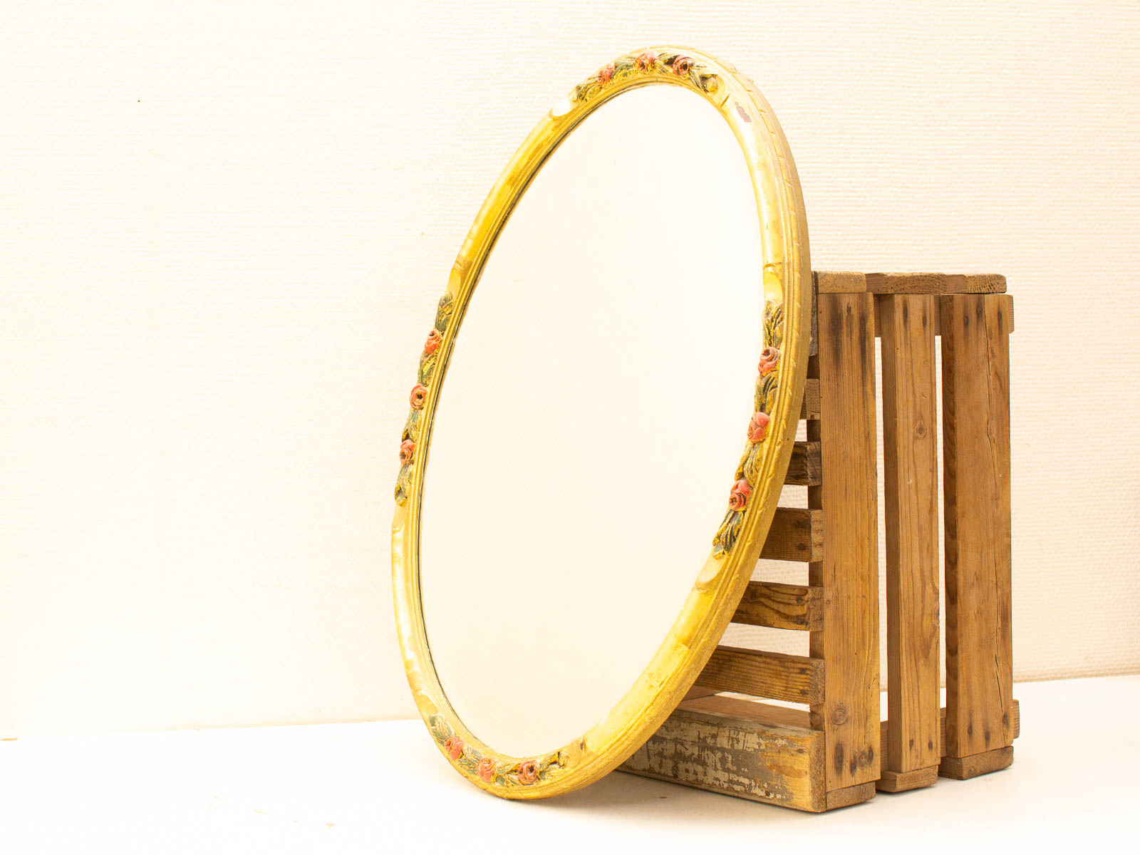 Elegant round mirror with golden frame and rustic wooden crate for stylish decor.