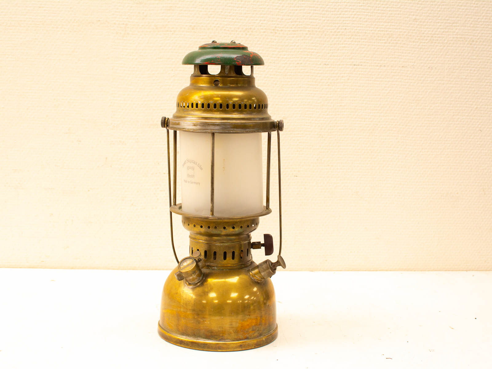 Antique brass kerosene lantern with green cap and frosted glass, perfect for collectors.