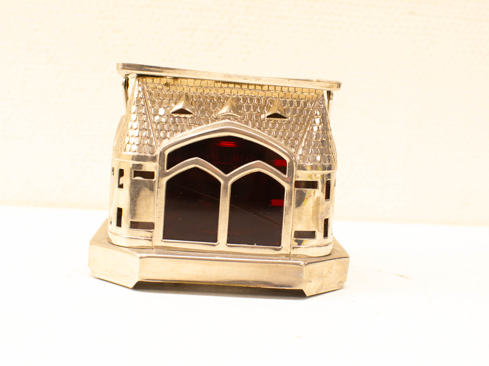 Elegant octagonal lantern with red glass windows and metallic details, perfect for home décor.