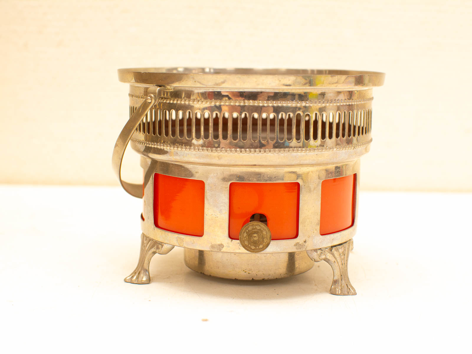 Vintage oil heater with orange panels, polished silver base, and elegant details for stylish decor.