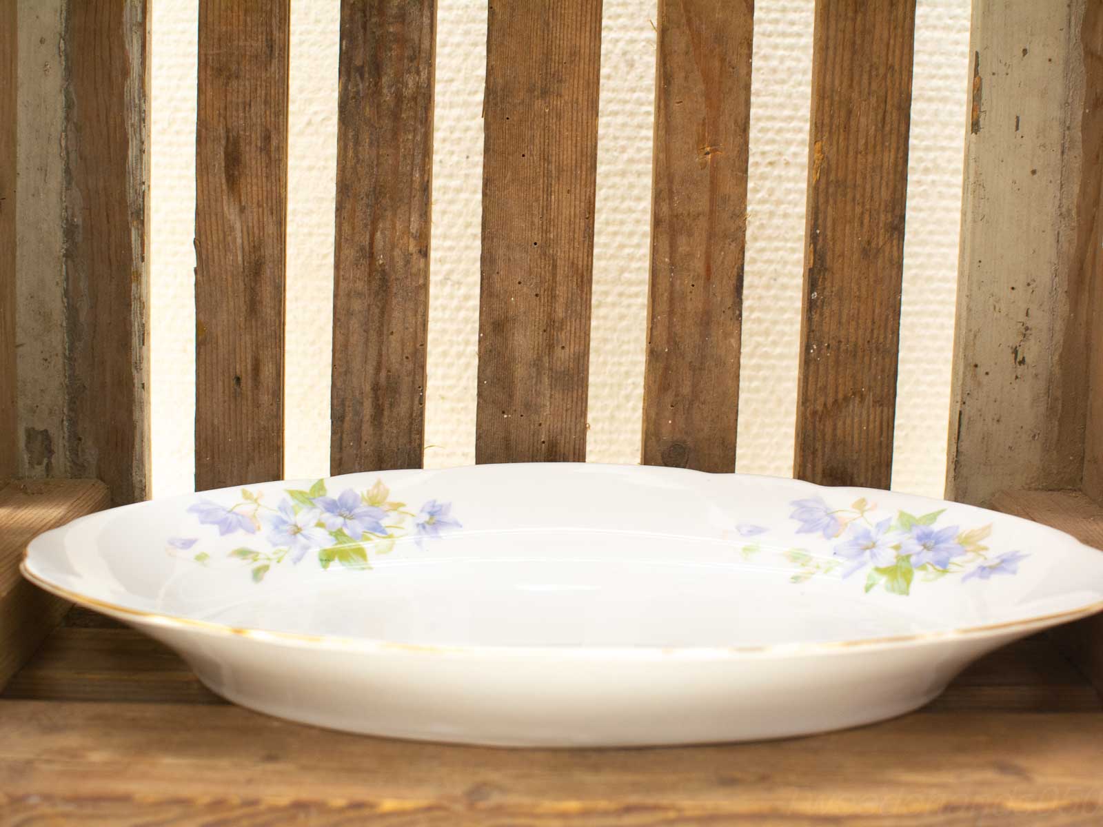 Elegant porcelain plate with blue floral design on rustic wooden surface.