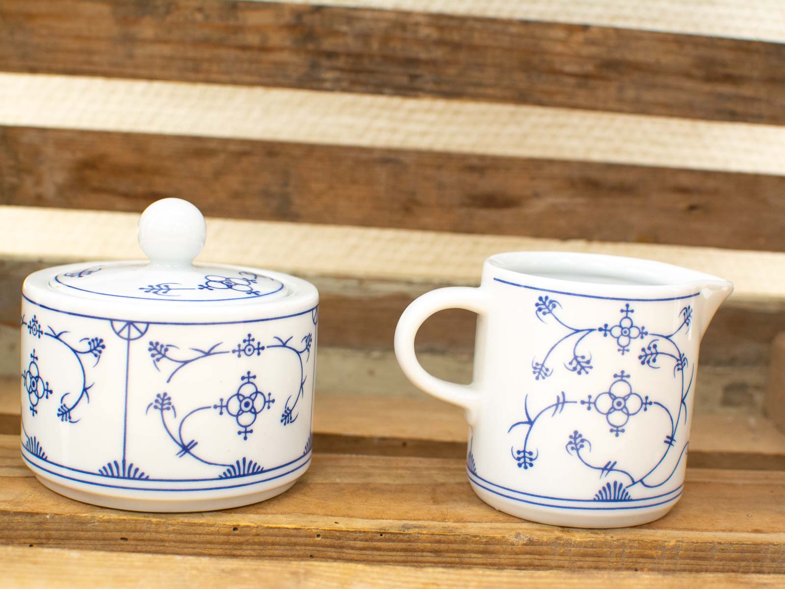 Elegant blue-and-white porcelain sugar bowl and creamer set with intricate floral designs.