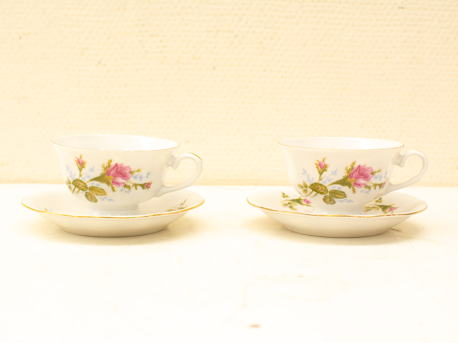 Elegant porcelain teacups with pink roses and gold rims for tea time and special occasions.