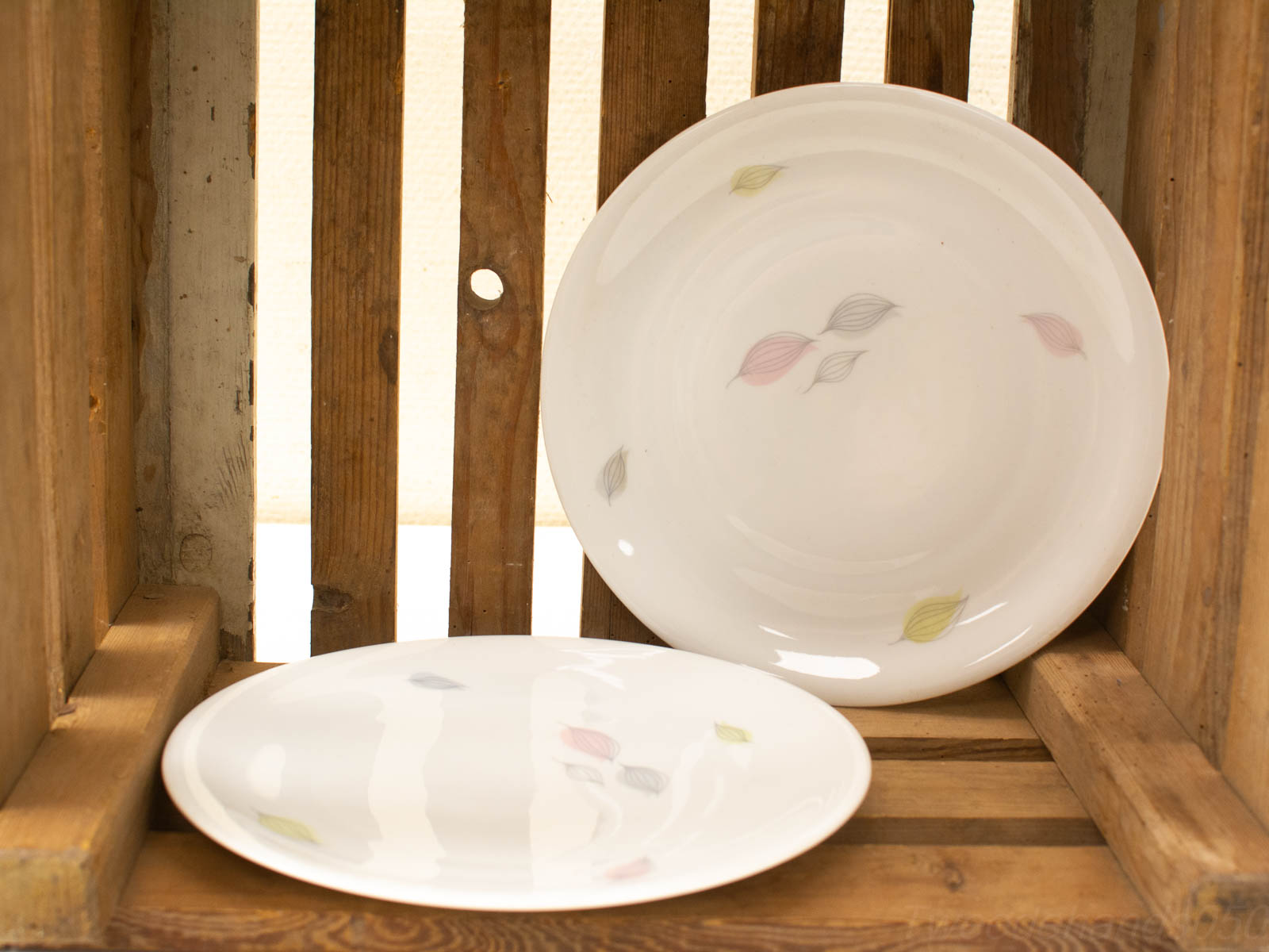 Elegant porcelain plates in a rustic wooden crate, perfect for home decor and gatherings.