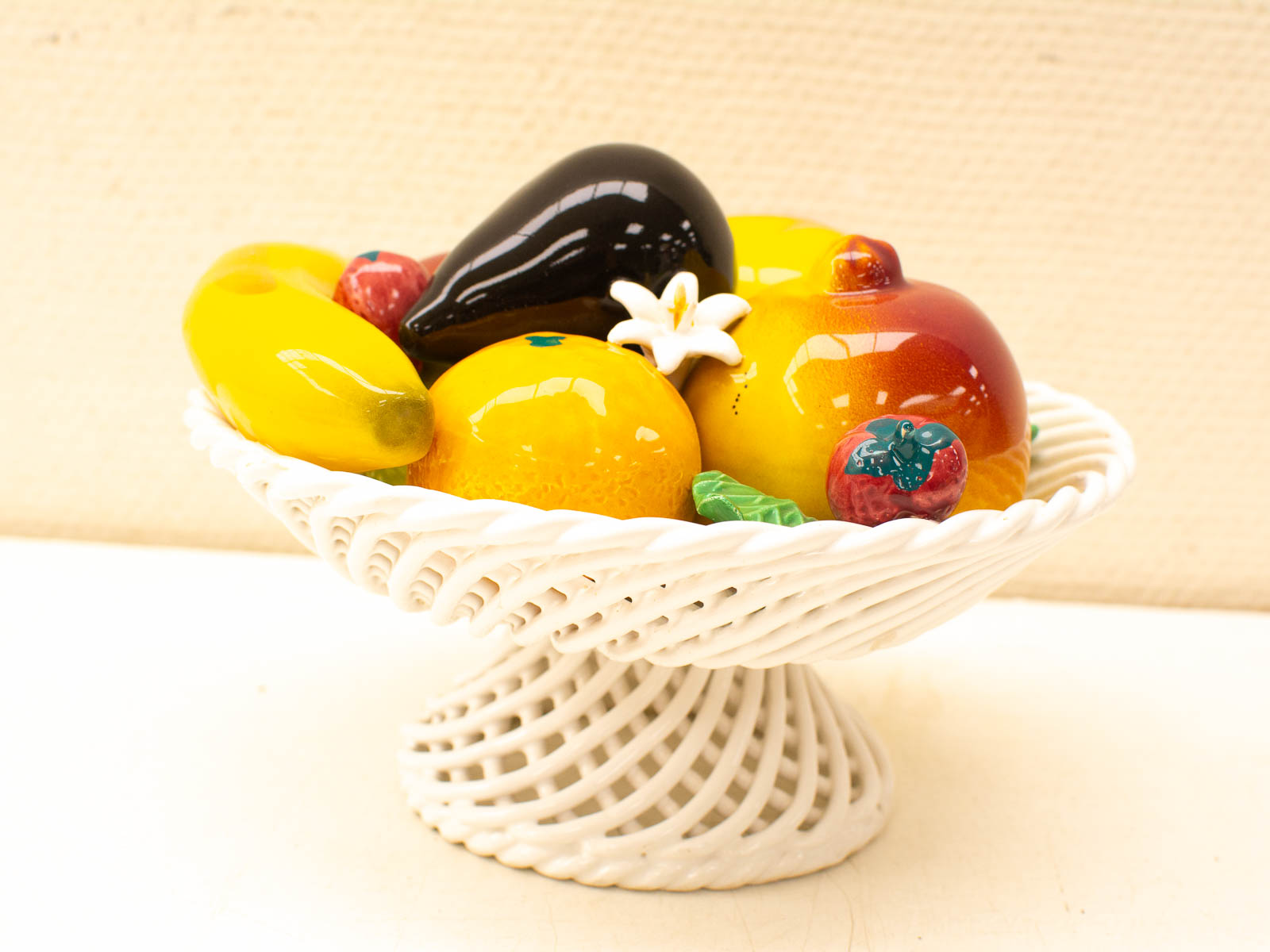 Elegant ceramic fruit bowl showcasing colorful fruits and a delicate flower for charming decor.