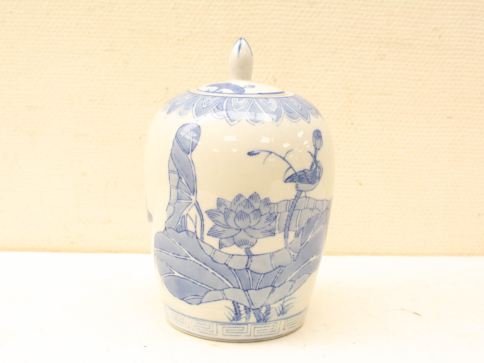 Elegant ceramic jar with lotus design, glossy finish, perfect for decor or storage.