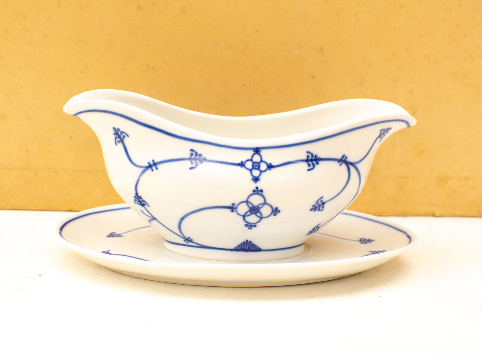 Elegant blue and white porcelain gravy boat with saucer, perfect for any dining occasion.