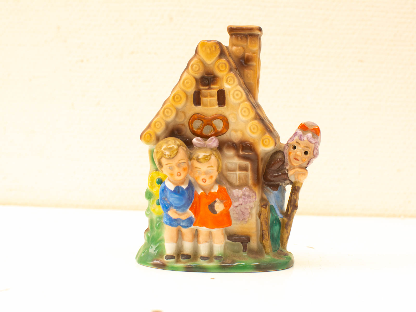 Whimsical ceramic figurine of playful children by a vintage house with a pretzel design.