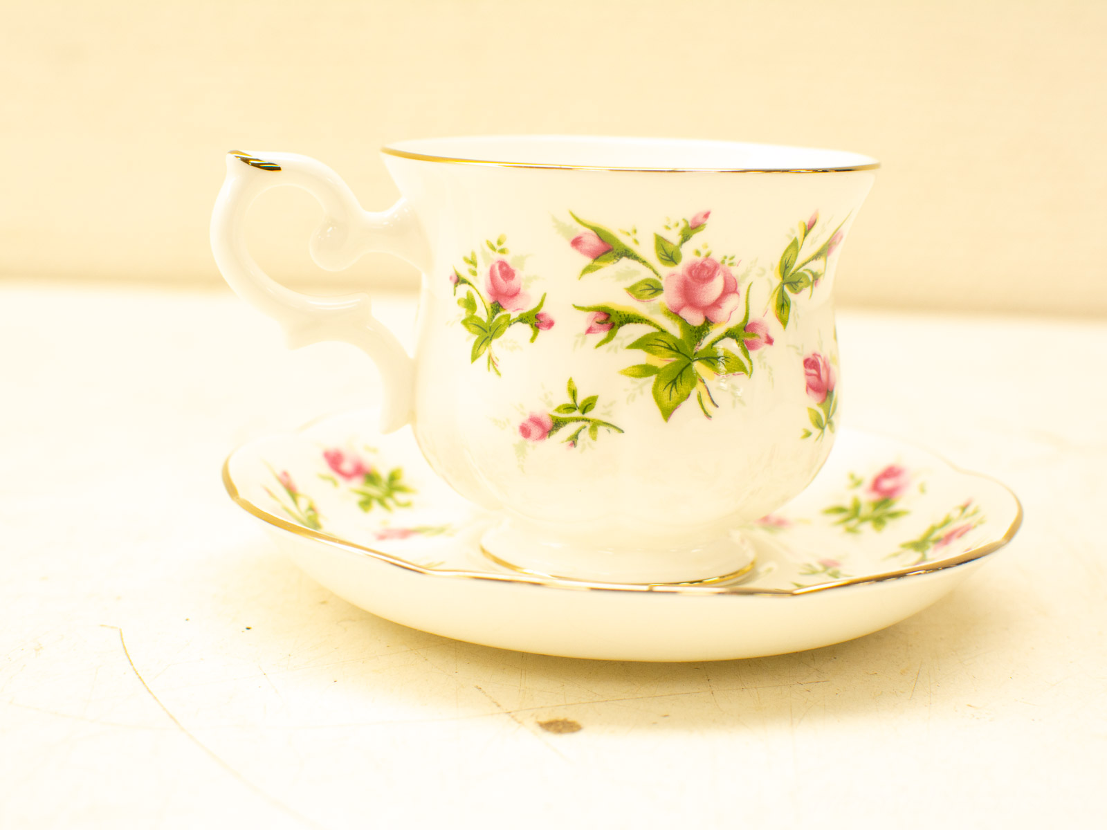 Elegant porcelain tea cup and saucer set with pink roses and gold trim. Perfect for tea parties.