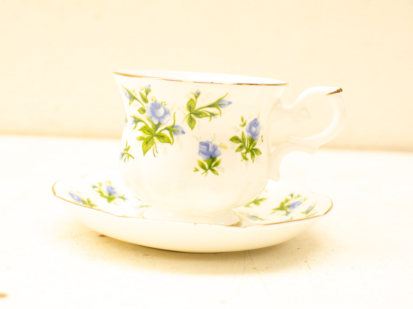 Elegant vintage tea cup and saucer set with blue roses and gold accents. Perfect for tea time.