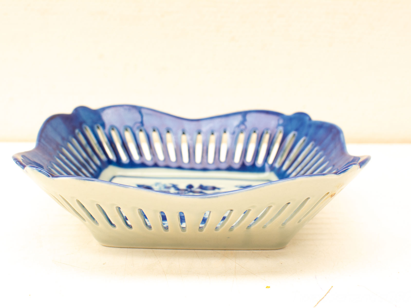 Elegant blue and white ceramic dish with scalloped edges and intricate floral patterns.