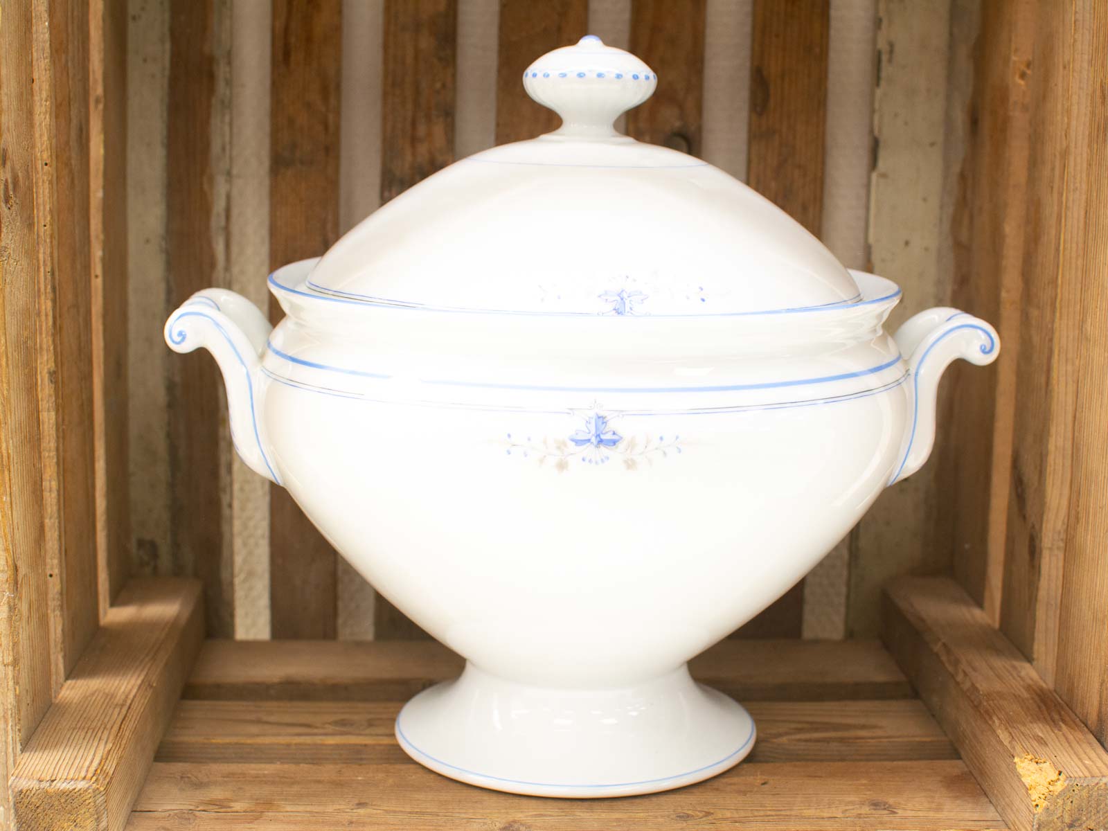 Elegant porcelain tureen with blue floral designs, perfect for serving or decoration against rustic wood.