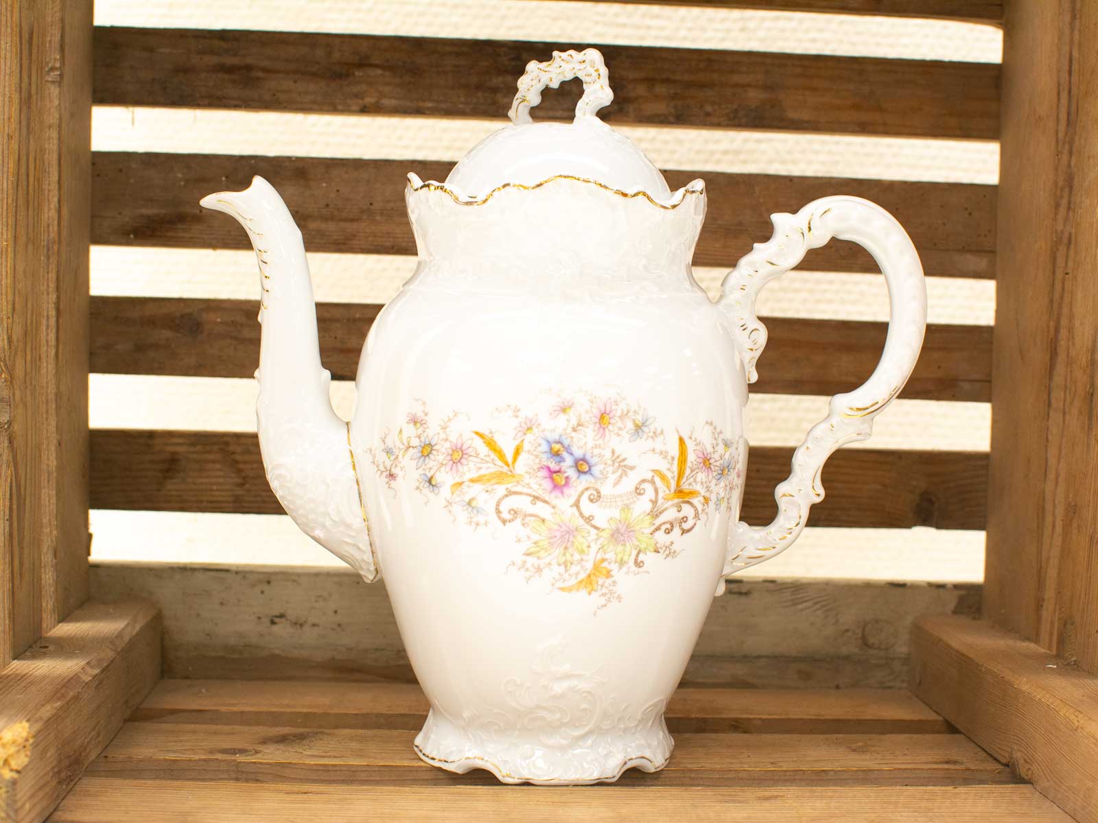 Vintage porcelain teapot with floral design, elegant shape, and ornate handle for tea lovers.