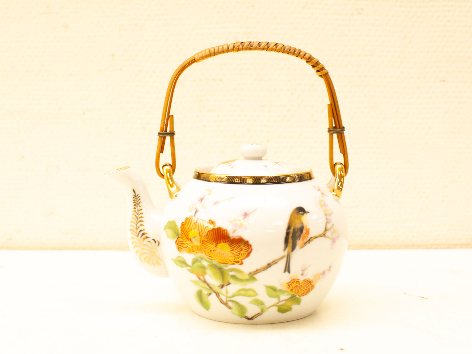 Elegant vintage porcelain teapot with floral designs, bamboo handle, and gold accents for tea enthusiasts.