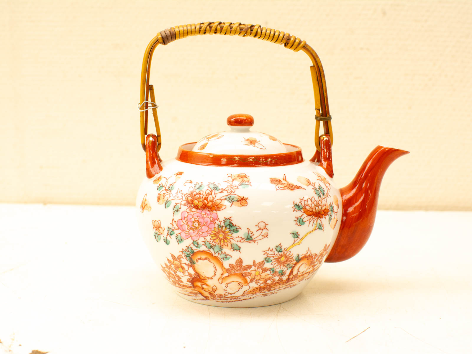 Elegant porcelain teapot with vibrant floral patterns and a stylish bamboo handle.