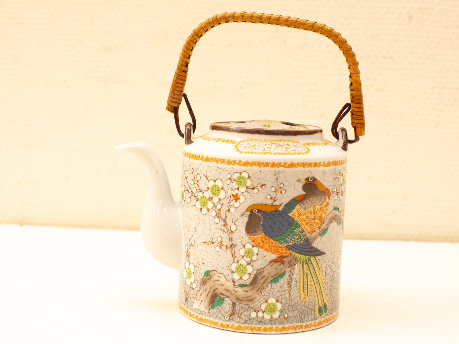 Elegant porcelain teapot with vibrant bird and floral designs, perfect for any table setting.