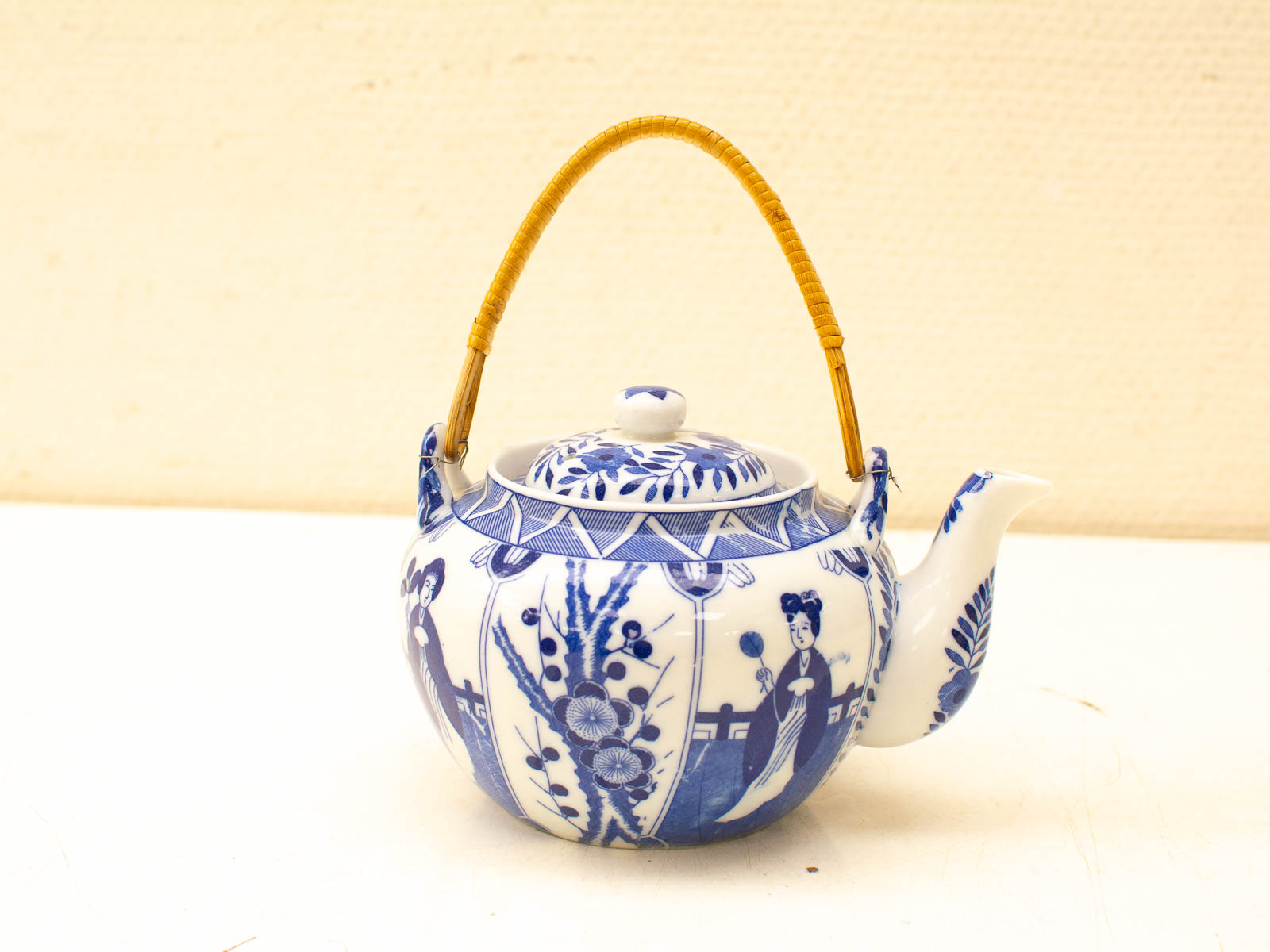 Elegant blue-and-white porcelain teapot with bamboo handle, perfect for tea ceremonies and display.