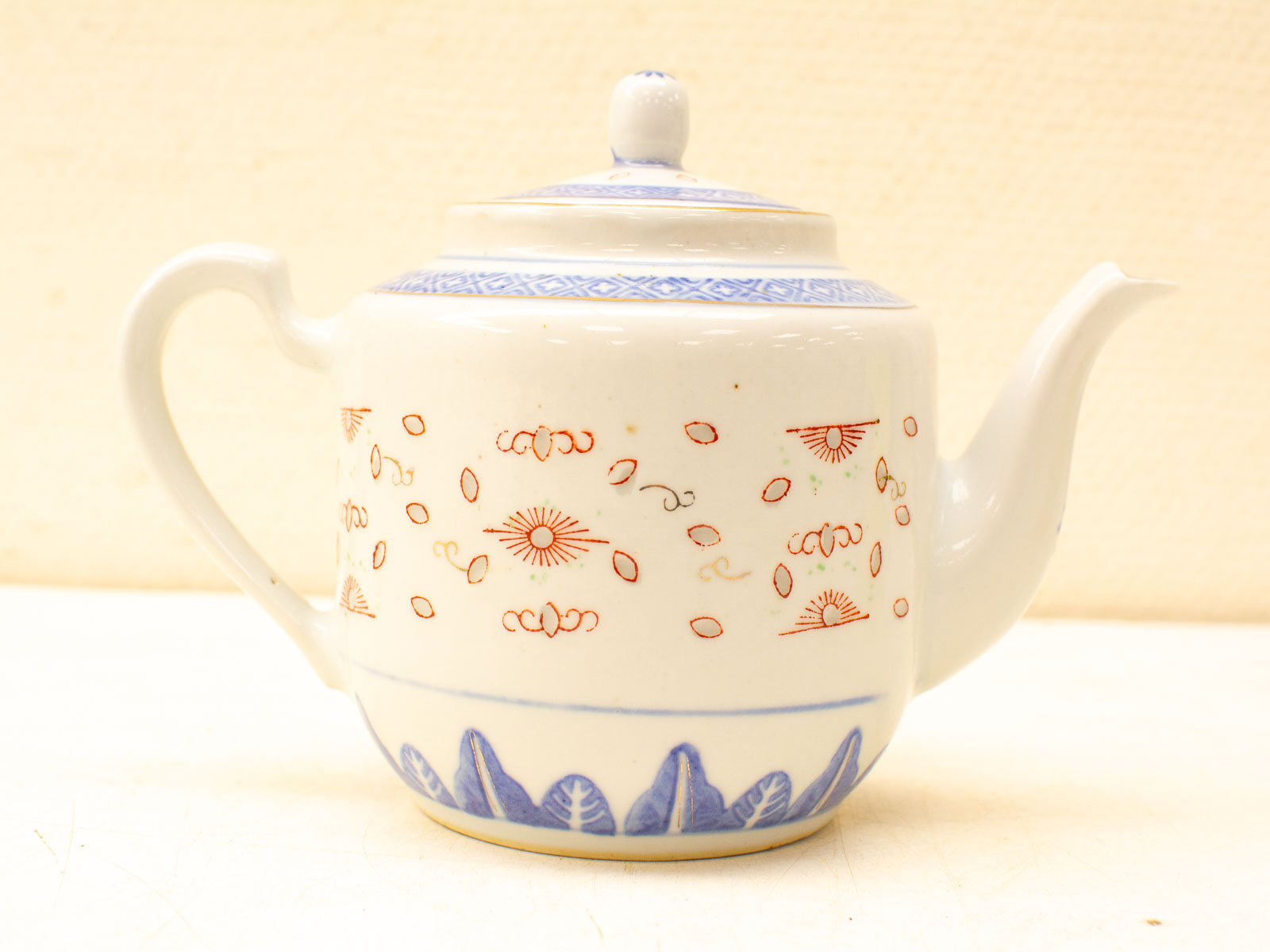 Charming porcelain teapot with elegant red and blue patterns, perfect for tea enthusiasts.