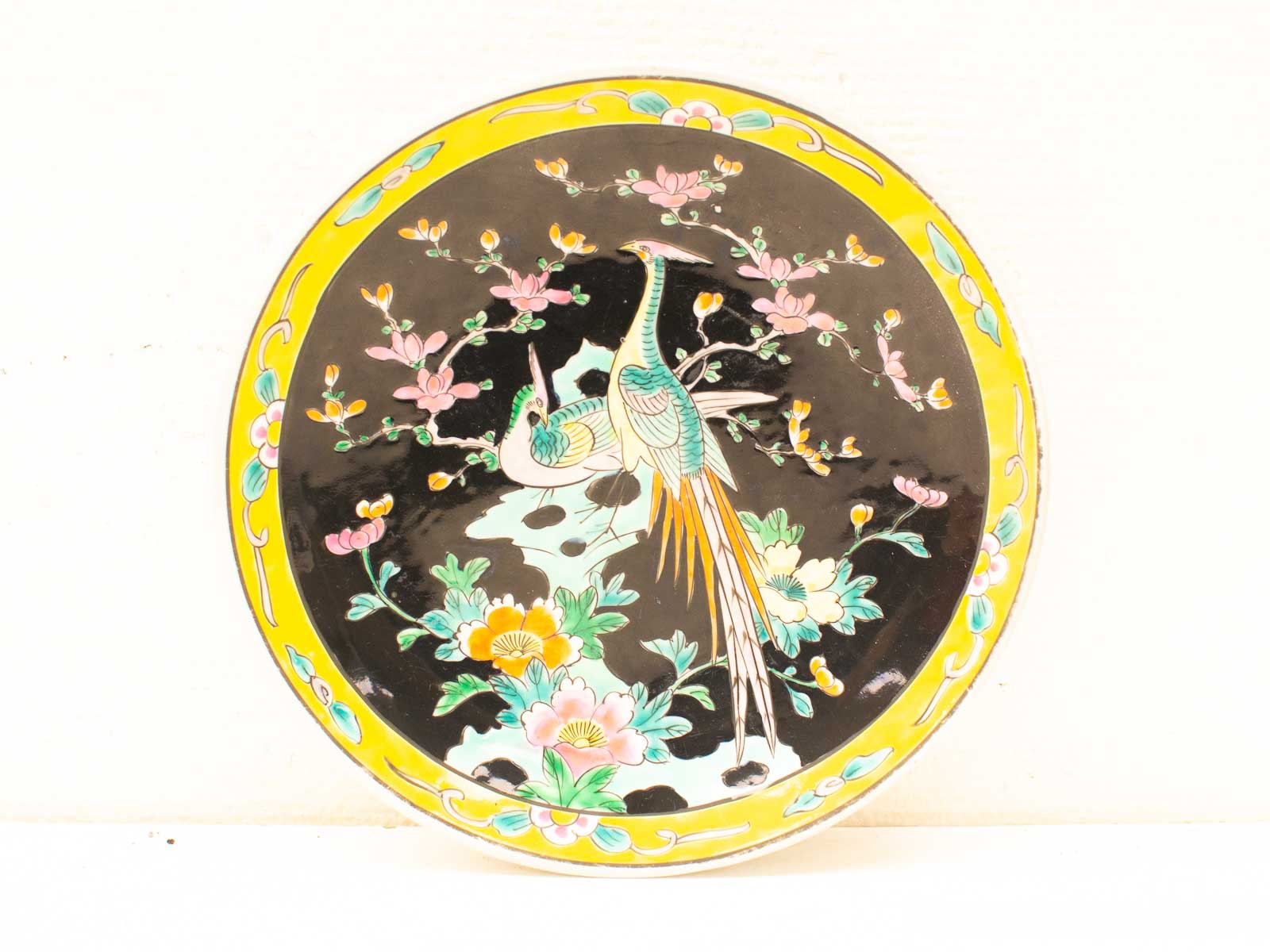 Vibrant decorative plate with intricately painted birds and flowers, showcasing exquisite craftsmanship and color.