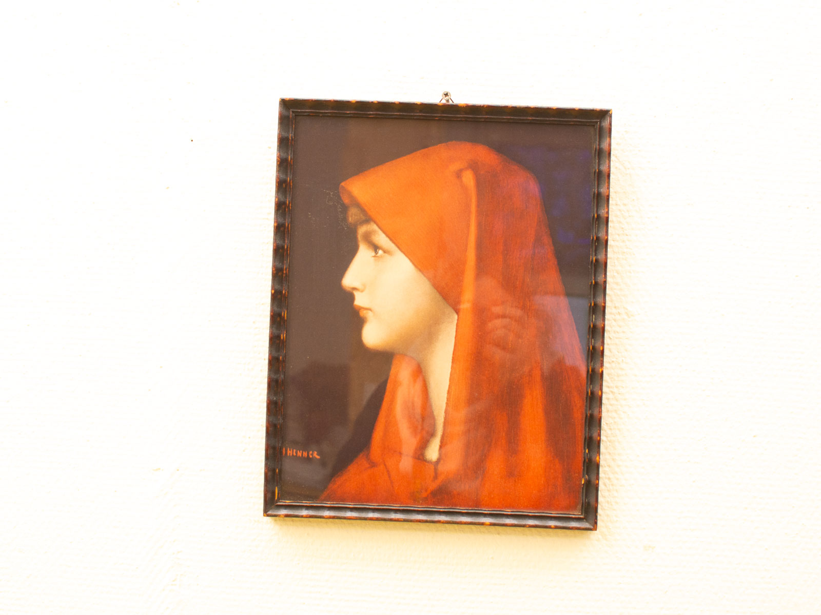 Young woman in a red hood, serene profile against a deep blue background.