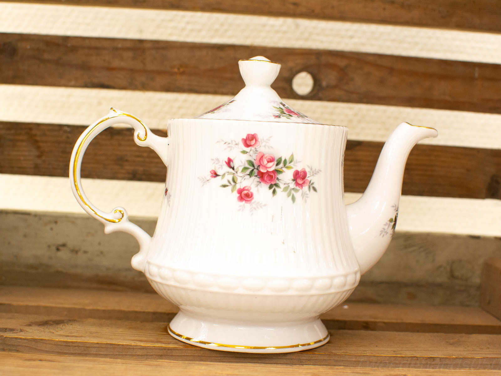 Elegant vintage porcelain teapot with rose pattern and gold accents, perfect for tea and decor.