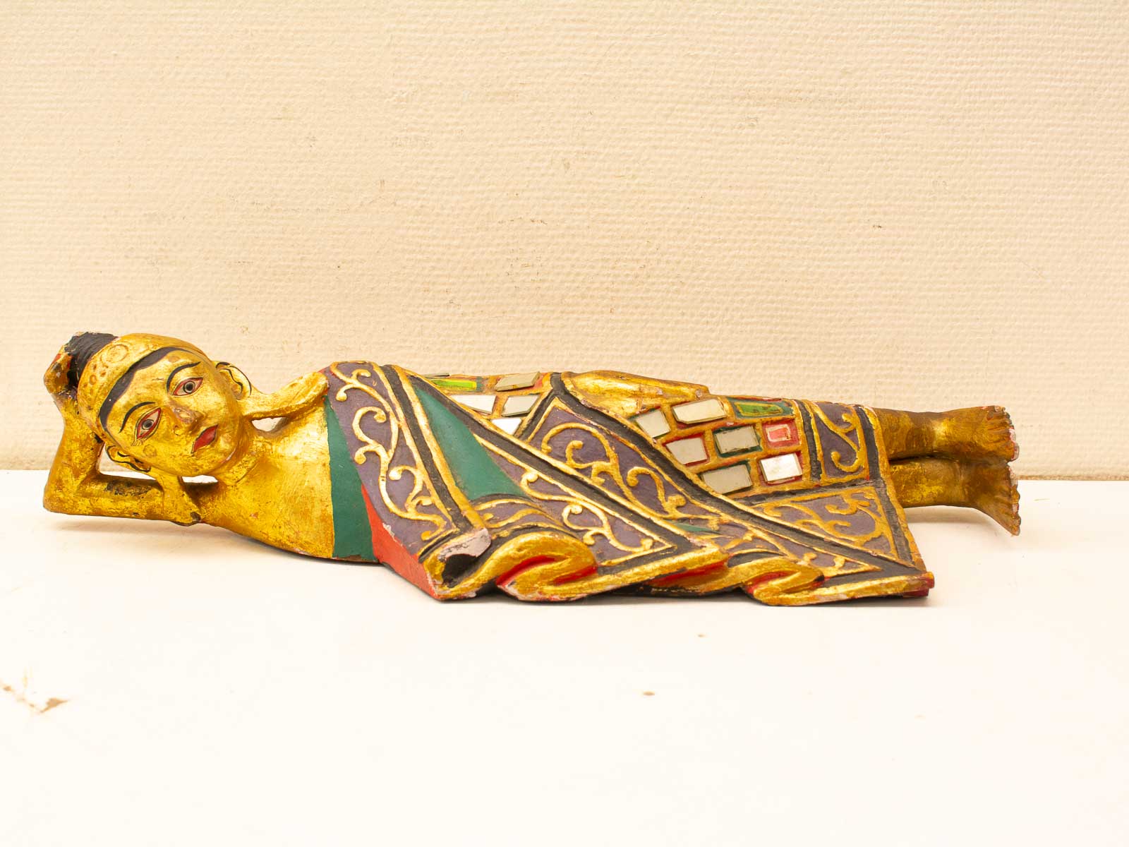 Exquisite Asian wooden sculpture of a serene reclining figure, showcasing intricate craftsmanship and vibrant colors.