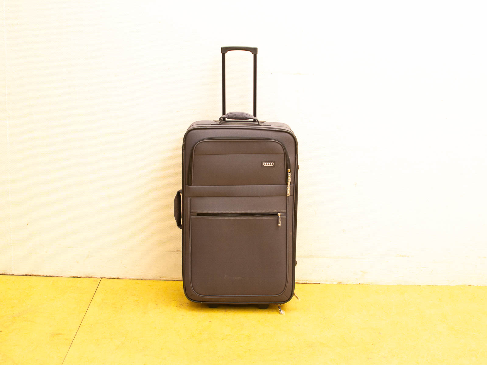 Sleek dark gray suitcase with wheels and zippered pockets, ideal for stylish travel.