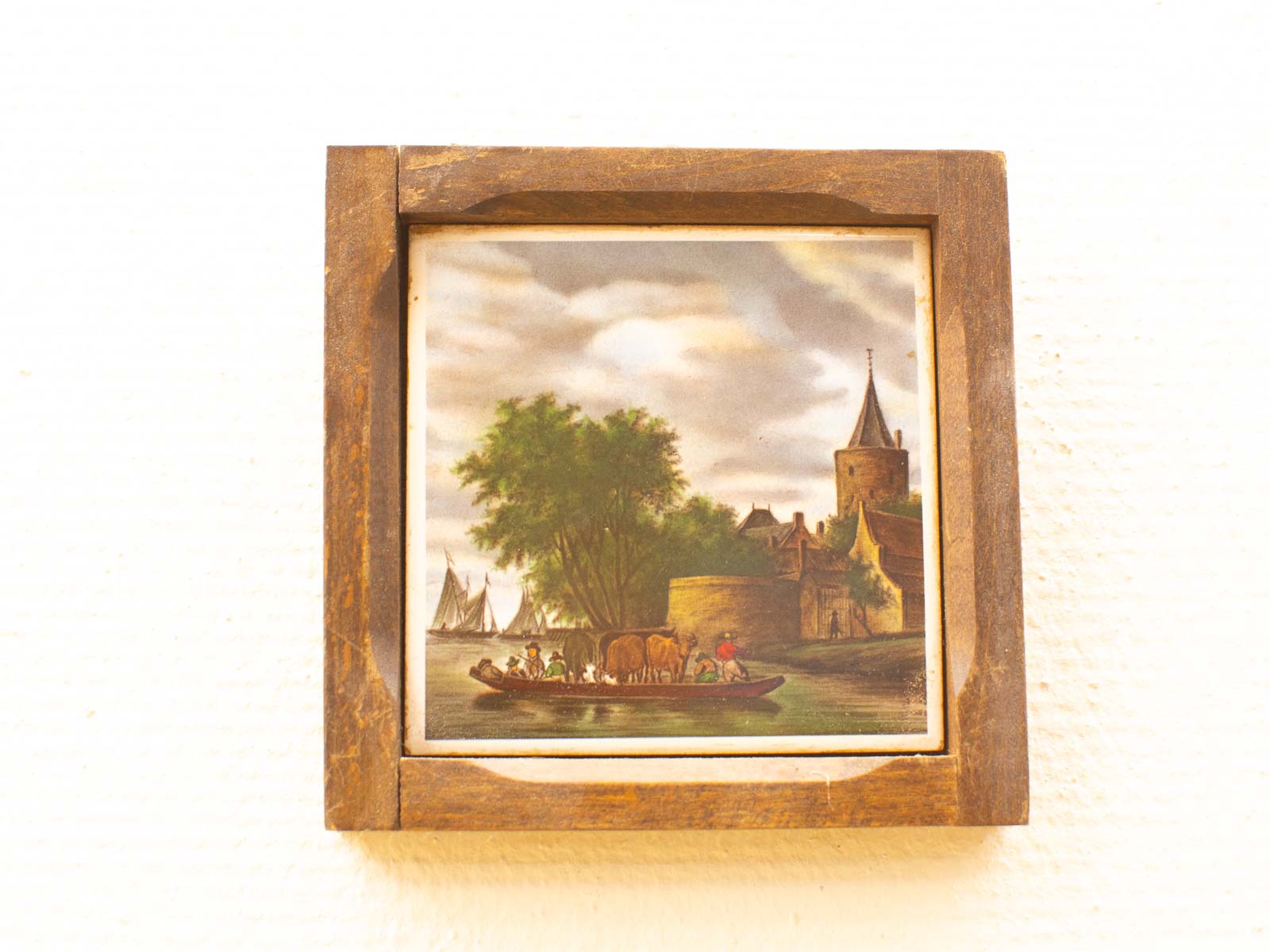 Charming vintage artwork of a tranquil riverside with a boat, cows, and a medieval village.