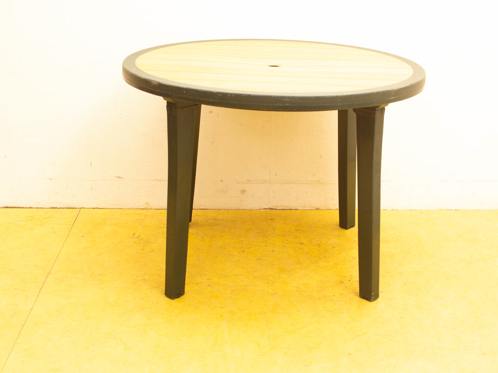 Modern round wooden table with umbrella hole and green legs, perfect for indoor and outdoor use.