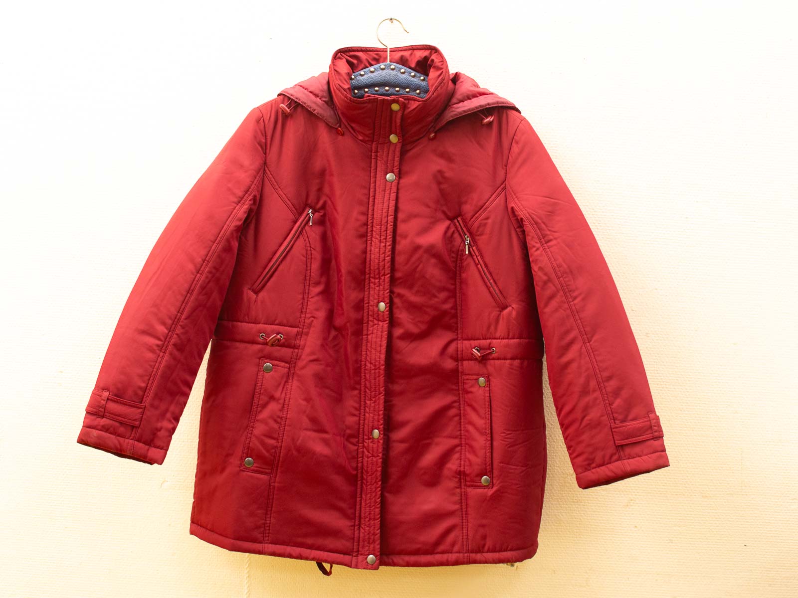 Vintage red quilted jacket with hood, perfect for cold weather and outdoor adventures.