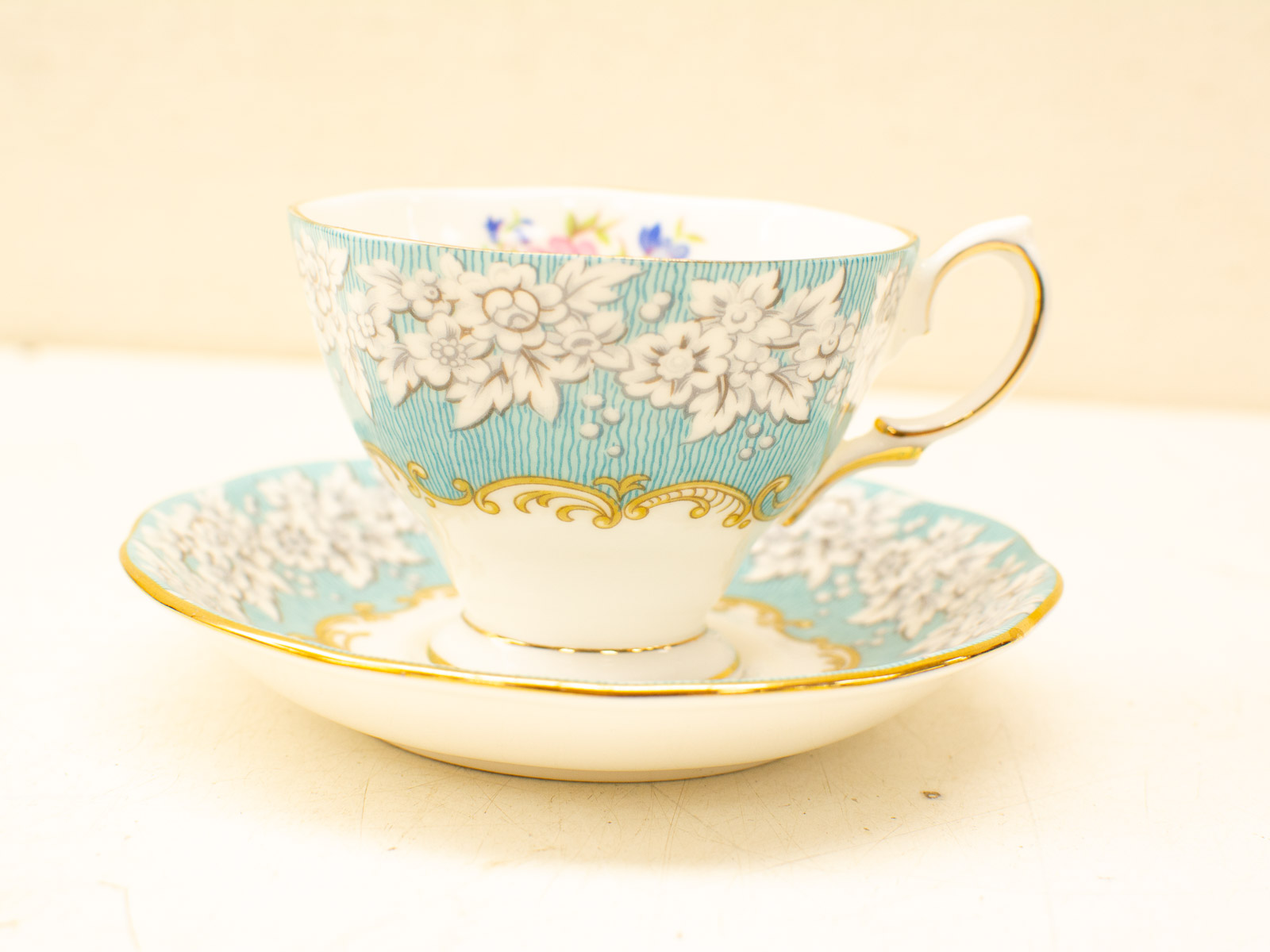 Elegant vintage teacup and saucer set with floral design in turquoise and gold accents.