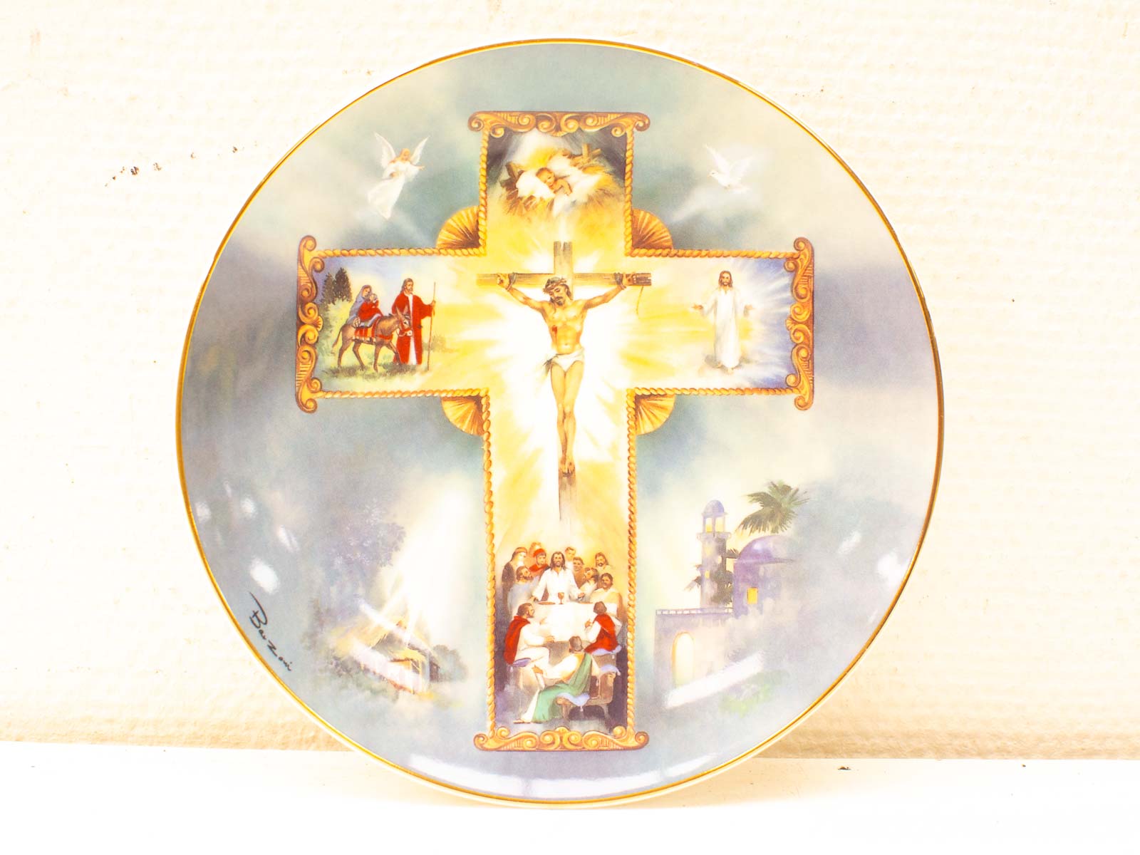 Decorative plate featuring a central cross, angels, and biblical scenes in serene colors.