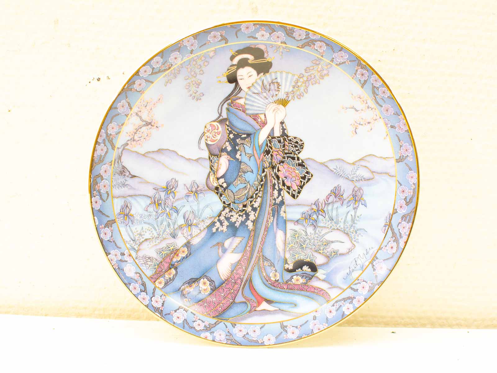 Graceful Japanese woman in vibrant kimono on decorative plate, celebrating traditional art and beauty.