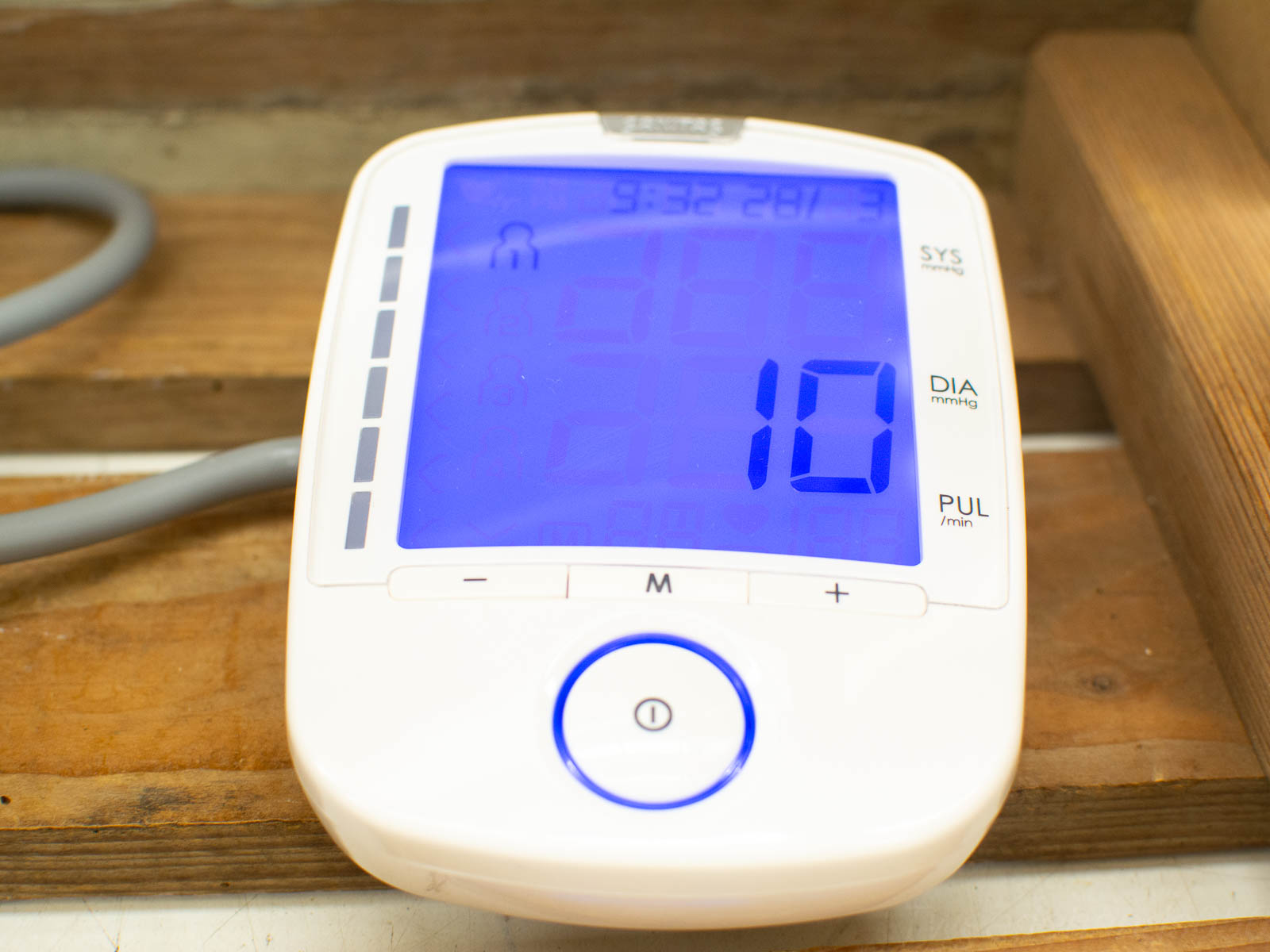 Modern blood pressure monitor with blue display on rustic wooden surface for easy health monitoring.