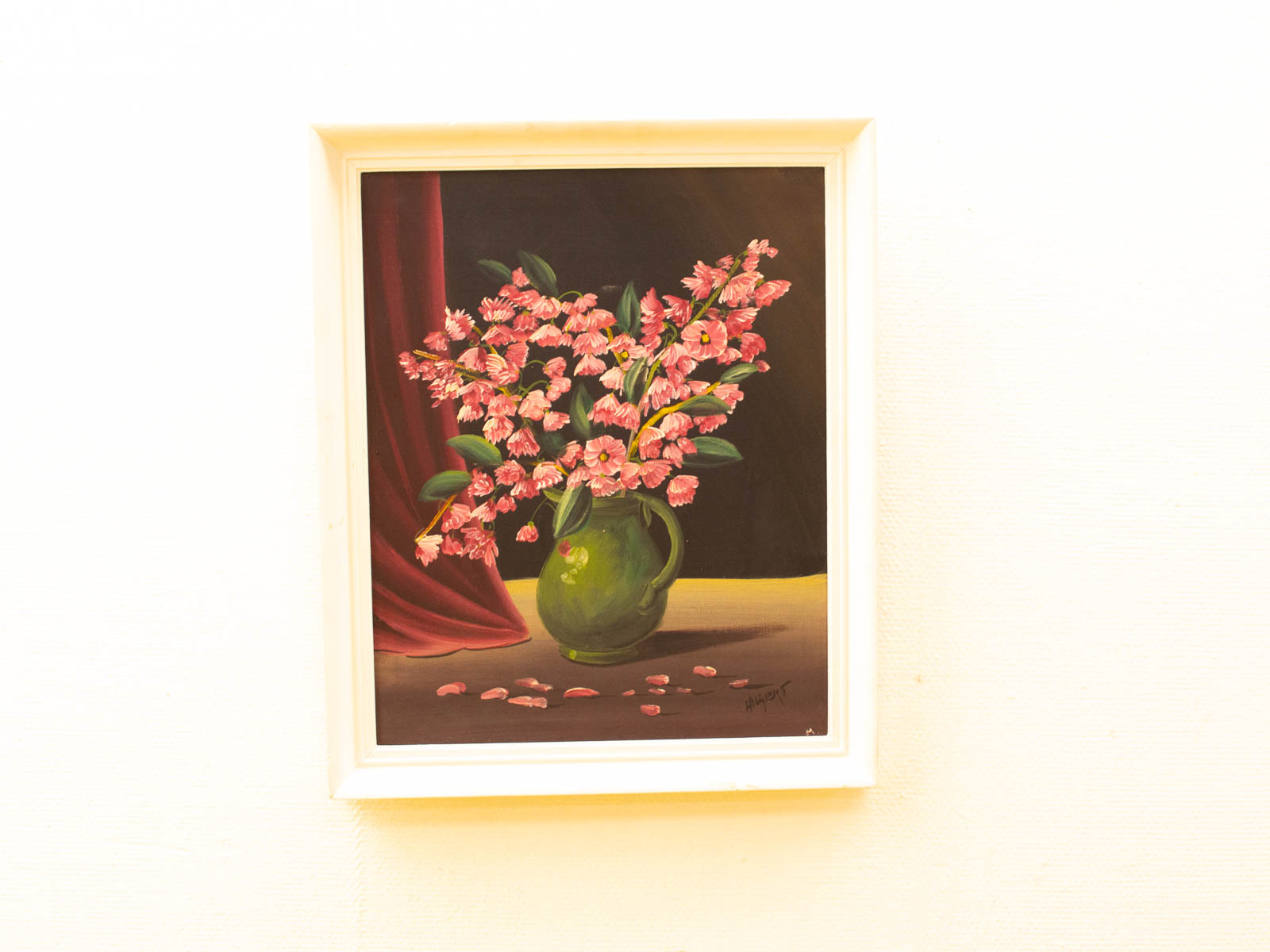 Vibrant pink flower bouquet in green vase with elegant red curtain backdrop.