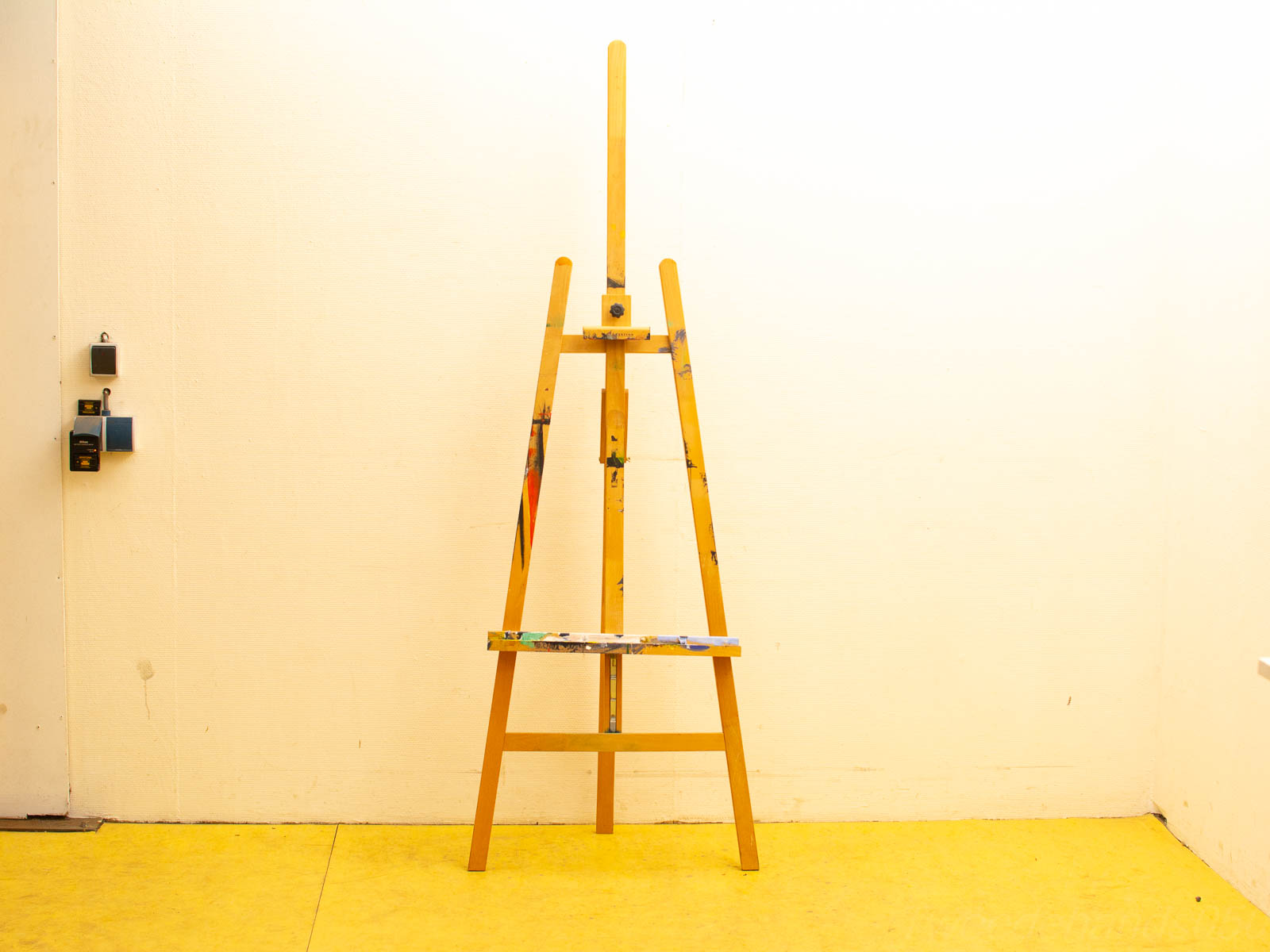 Serene minimalist artist workspace with a wooden easel and vibrant yellow floor.