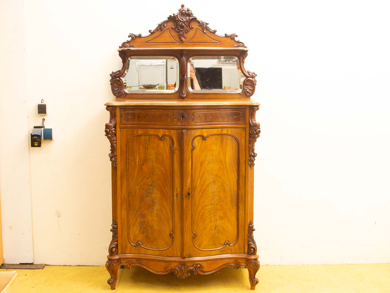 Elegant antique wooden cabinet with intricate carvings and mirrors, perfect for storage and decoration.