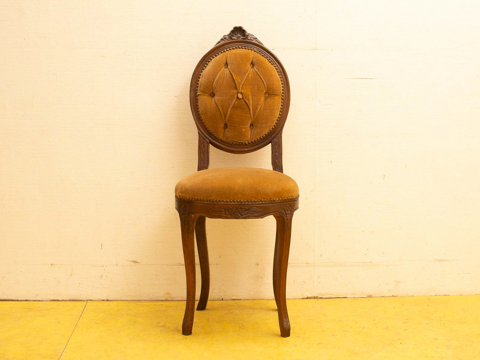 Elegant vintage chair with brown velvet upholstery and intricate wood carvings for timeless charm.