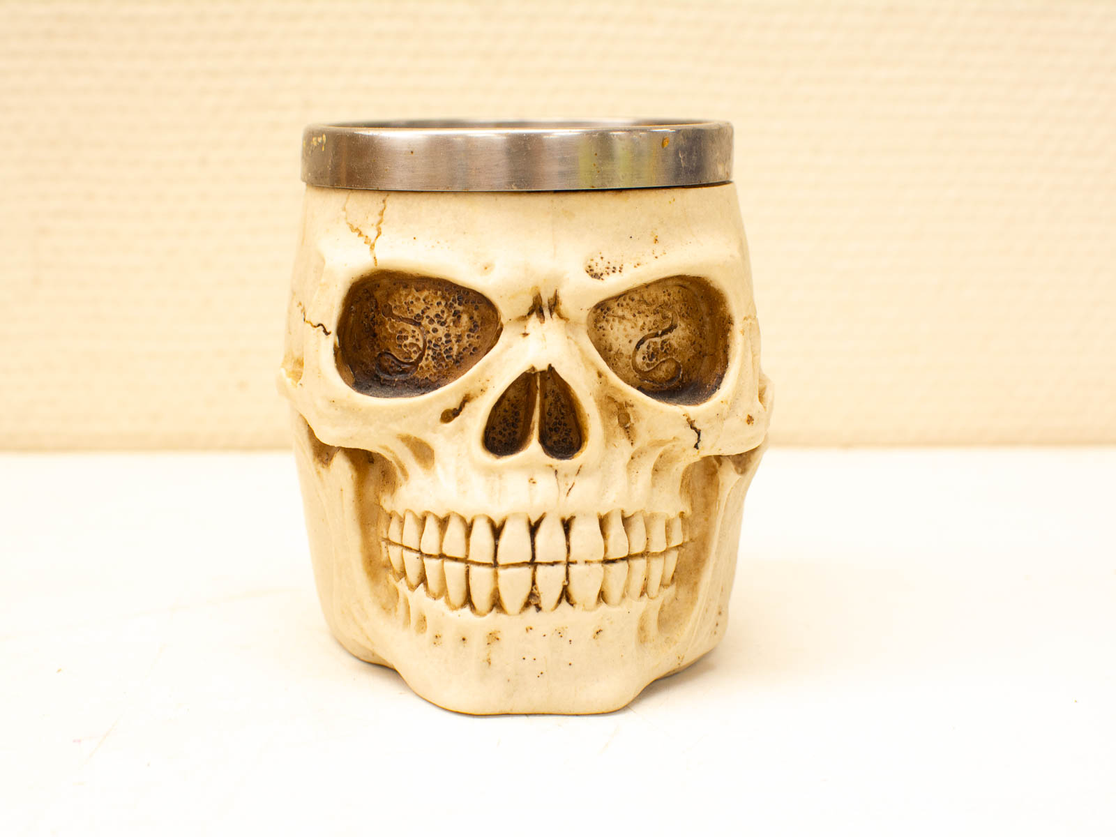 Unique bone-like skull mug with detailed design and stainless steel rim for stylish drinkware.