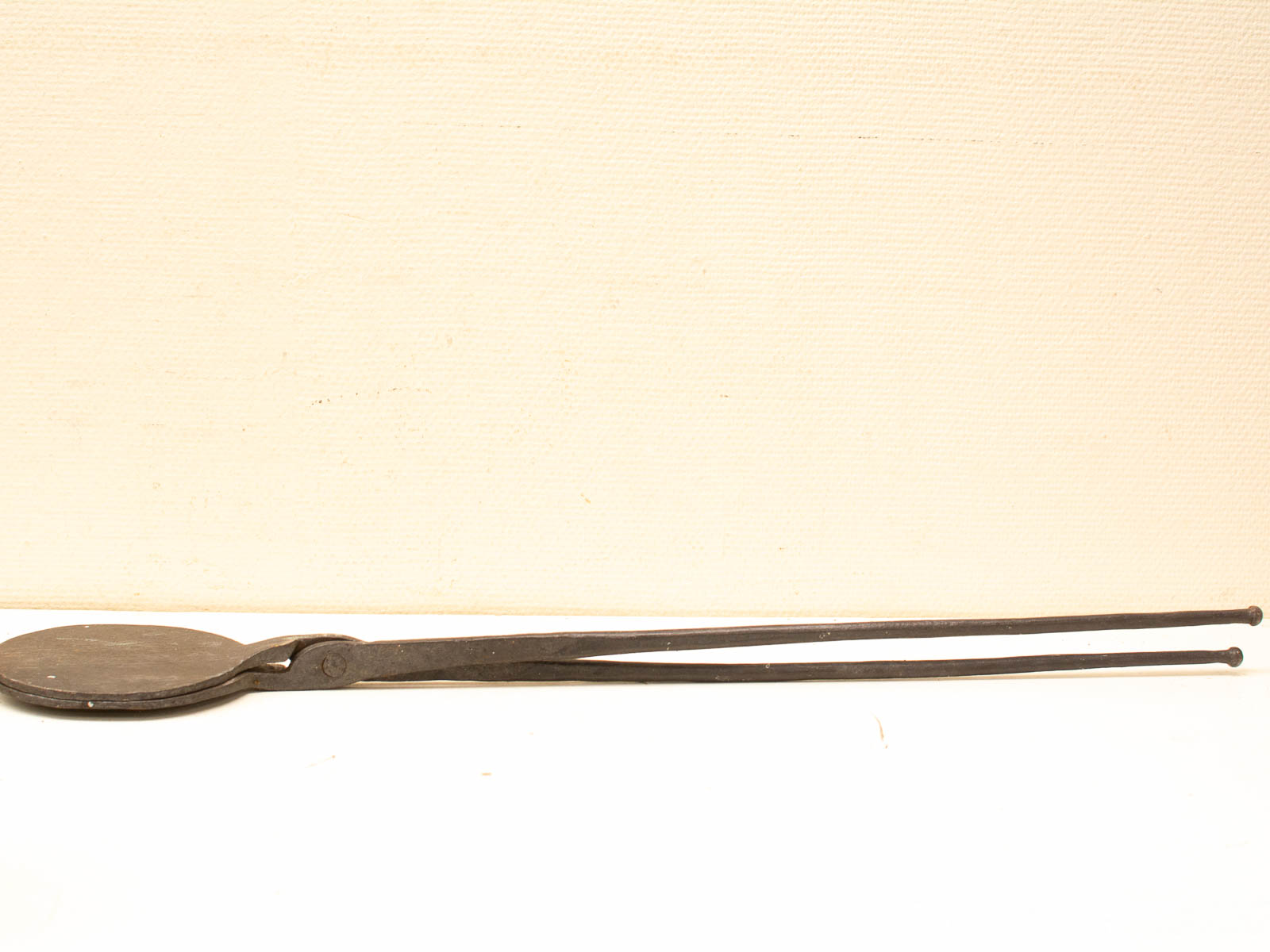 Antique wrought iron kitchen tongs, perfect for flipping and serving with rustic charm.