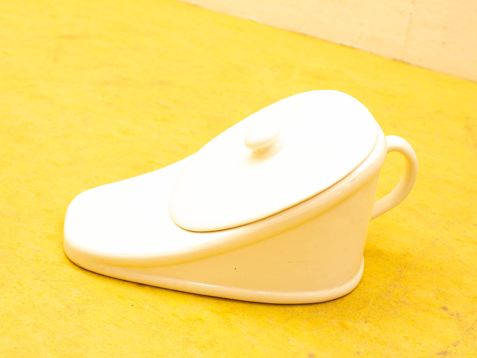 Whimsical shoe-shaped ceramic teapot, glossy white finish, perfect for adding charm to any table.