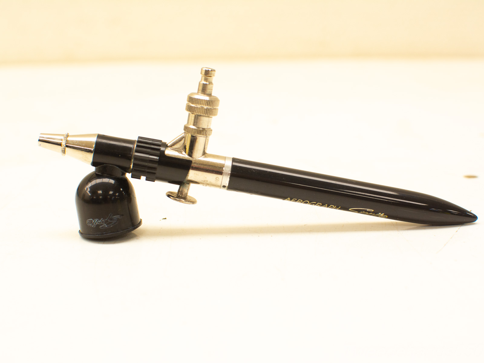 Professional black airbrush with metallic accents for precise art and cosmetic applications.