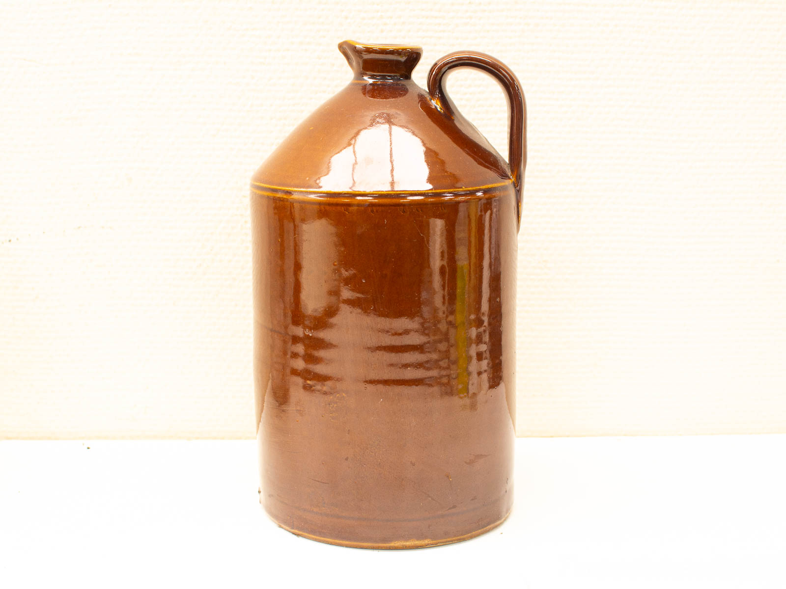 Classic brown ceramic jug with glossy glaze, sturdy handle, and timeless charm.