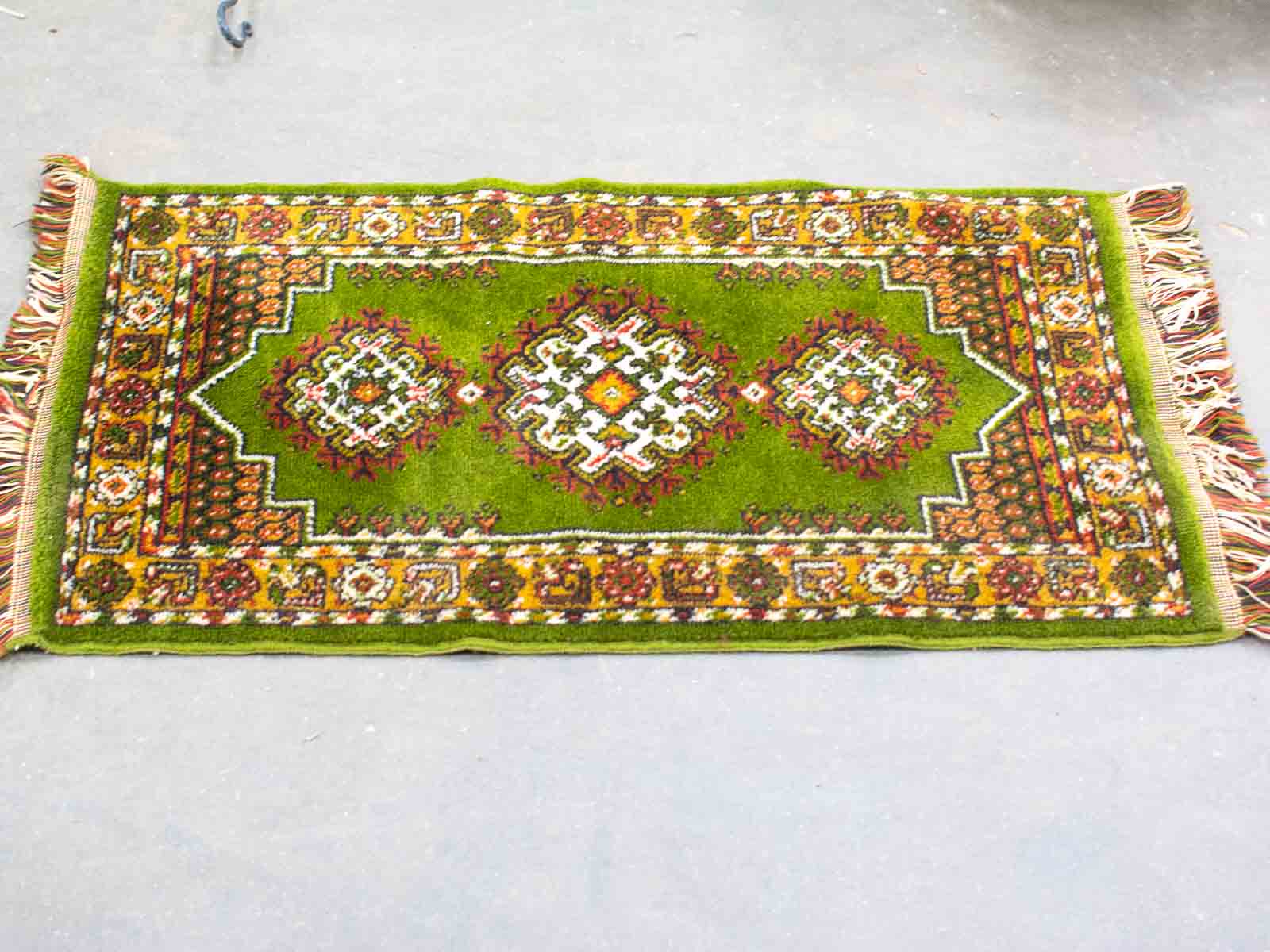 Vibrant green handwoven vintage rug with intricate red, yellow, and white patterns for any space.