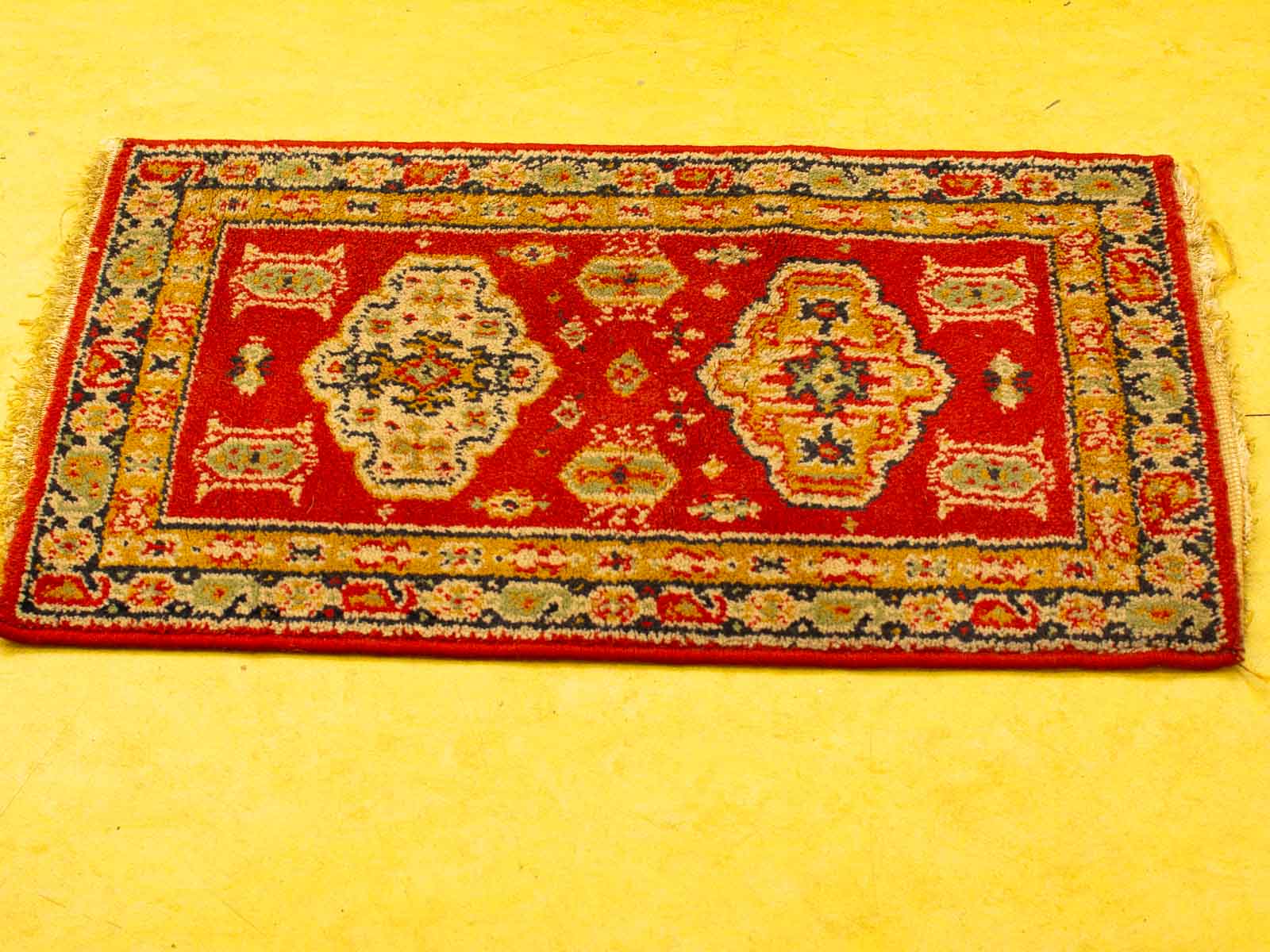 Vibrant red vintage rug with intricate patterns on cheerful yellow floor adds warmth and charm.