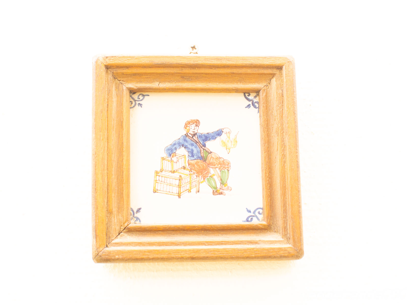 Charming vintage artwork of a tradesman with a bird in a rustic wooden frame.