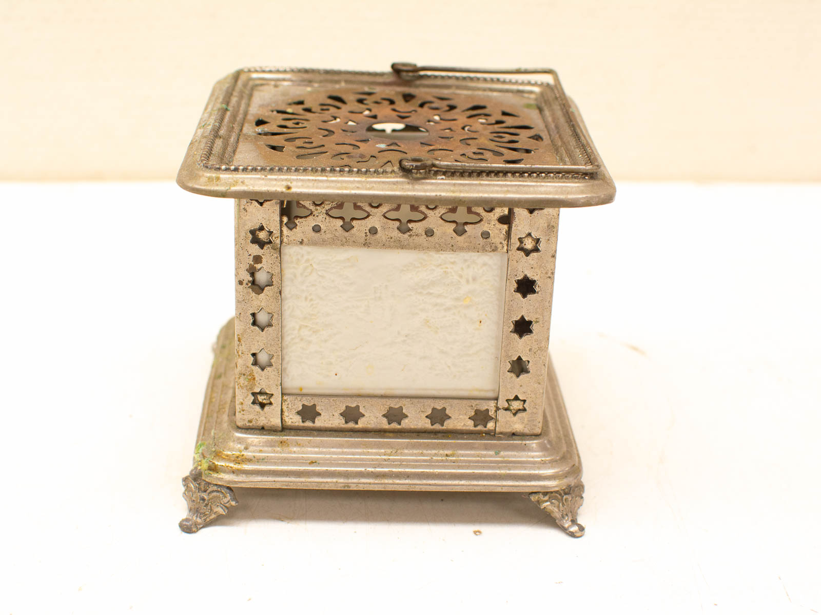 Vintage lantern with filigree designs, silver patina, and intricate light patterns for elegant decor.