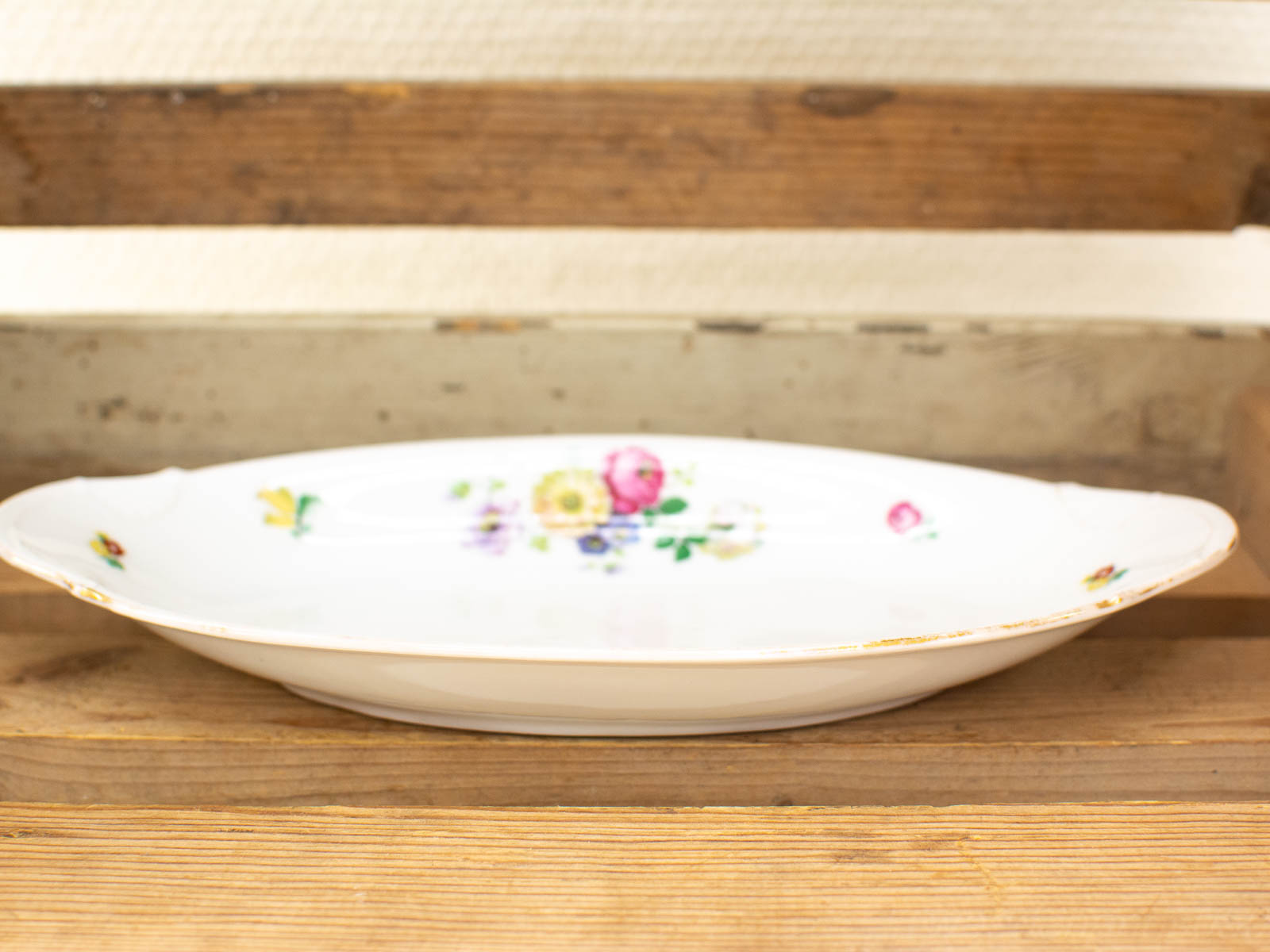 Vintage floral porcelain platter on rustic wood, perfect heirloom for timeless dining elegance.